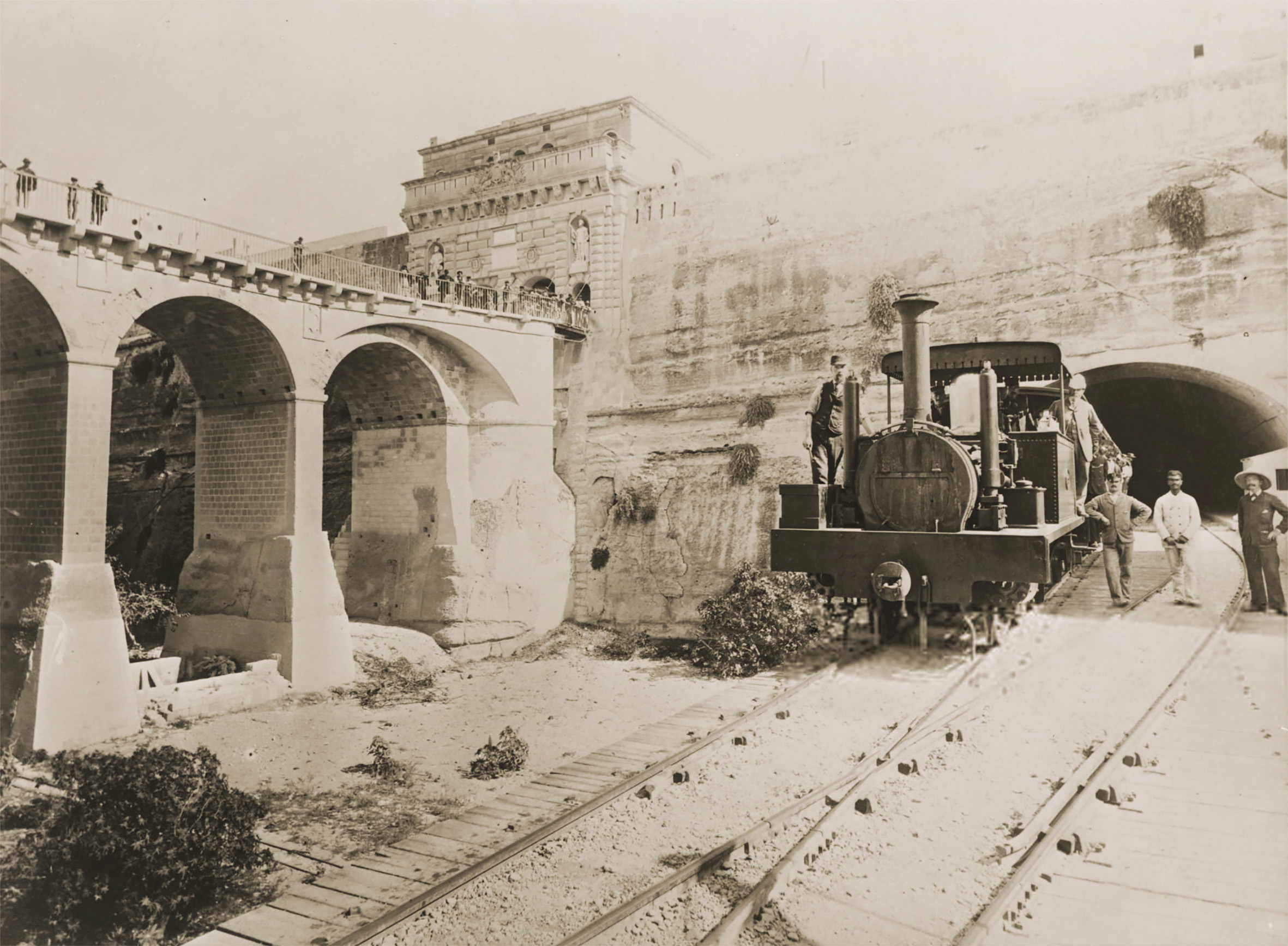 Another staged photo of the station at Valletta in 1883, probably another of the pre-opening trial runs of the railway. This photo gives some indication of the tiny size of the engines, lightweight trackwork, and basic bridge construction that led to the condition of the railway infrastructure declining fast when in-use.