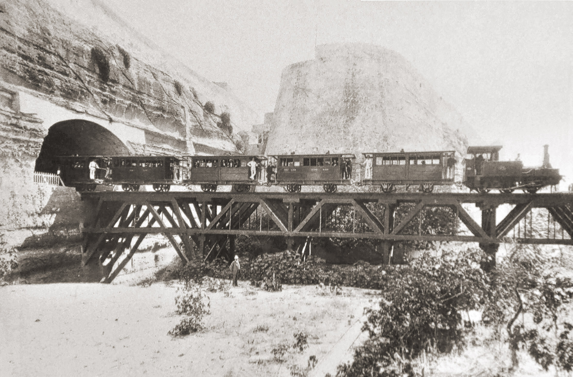 The timber viaduct across the main ditch to Valletta with a train posed crossing it. This was probably one of the test trains that preceded inauguration at the end of February 1883. The man standing in the ditch with the characteristic white helmet looks like it's engineer Frank Geneste.