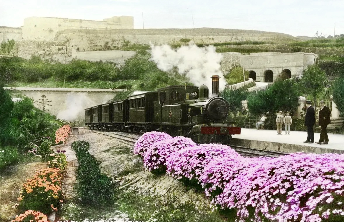 A Beyer Peacock locomotive of the Malta Railway steams uphill towards Museum Station with the walls of Mdina rising up behind.
